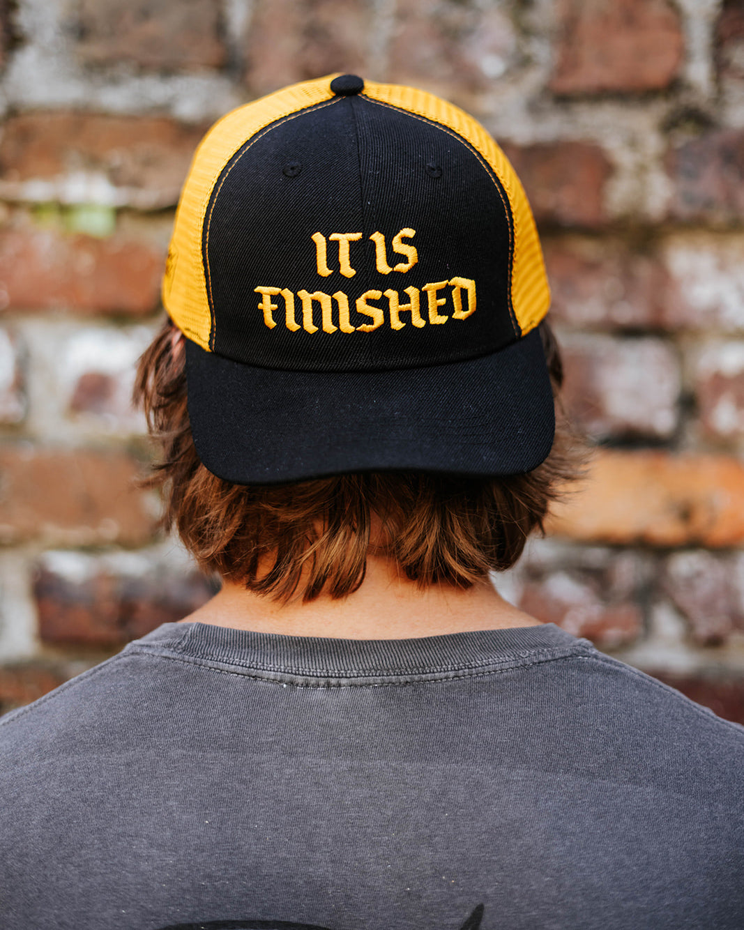 Gorra snapback negra y amarilla con la frase "It Is Finished"